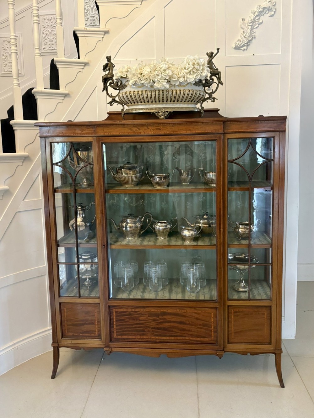 An Edwardian inlaid mahogany display cabinet featuring three glazed doors with decorative glazing bars and a fabric-lined interior. View IX
