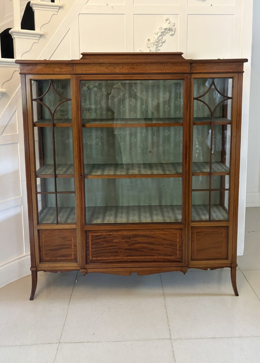 An Edwardian inlaid mahogany display cabinet featuring three glazed doors with decorative glazing bars and a fabric-lined interior. View XI