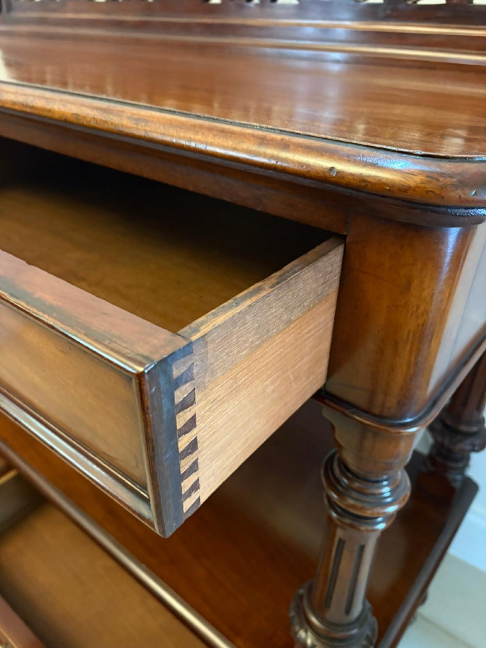 A Victorian mahogany buffet server featuring an openwork carved gallery back, four drawer compartments, turned columns, and an open lower shelf. View V