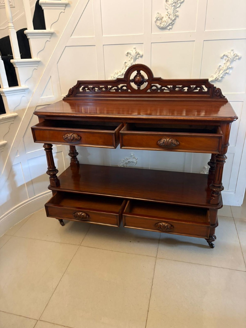 A Victorian mahogany buffet server featuring an openwork carved gallery back, four drawer compartments, turned columns, and an open lower shelf. View IX