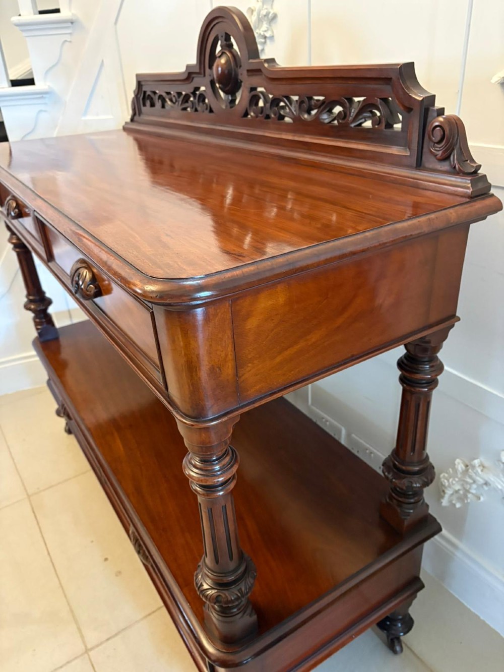 A Victorian mahogany buffet server featuring an openwork carved gallery back, four drawer compartments, turned columns, and an open lower shelf. View X