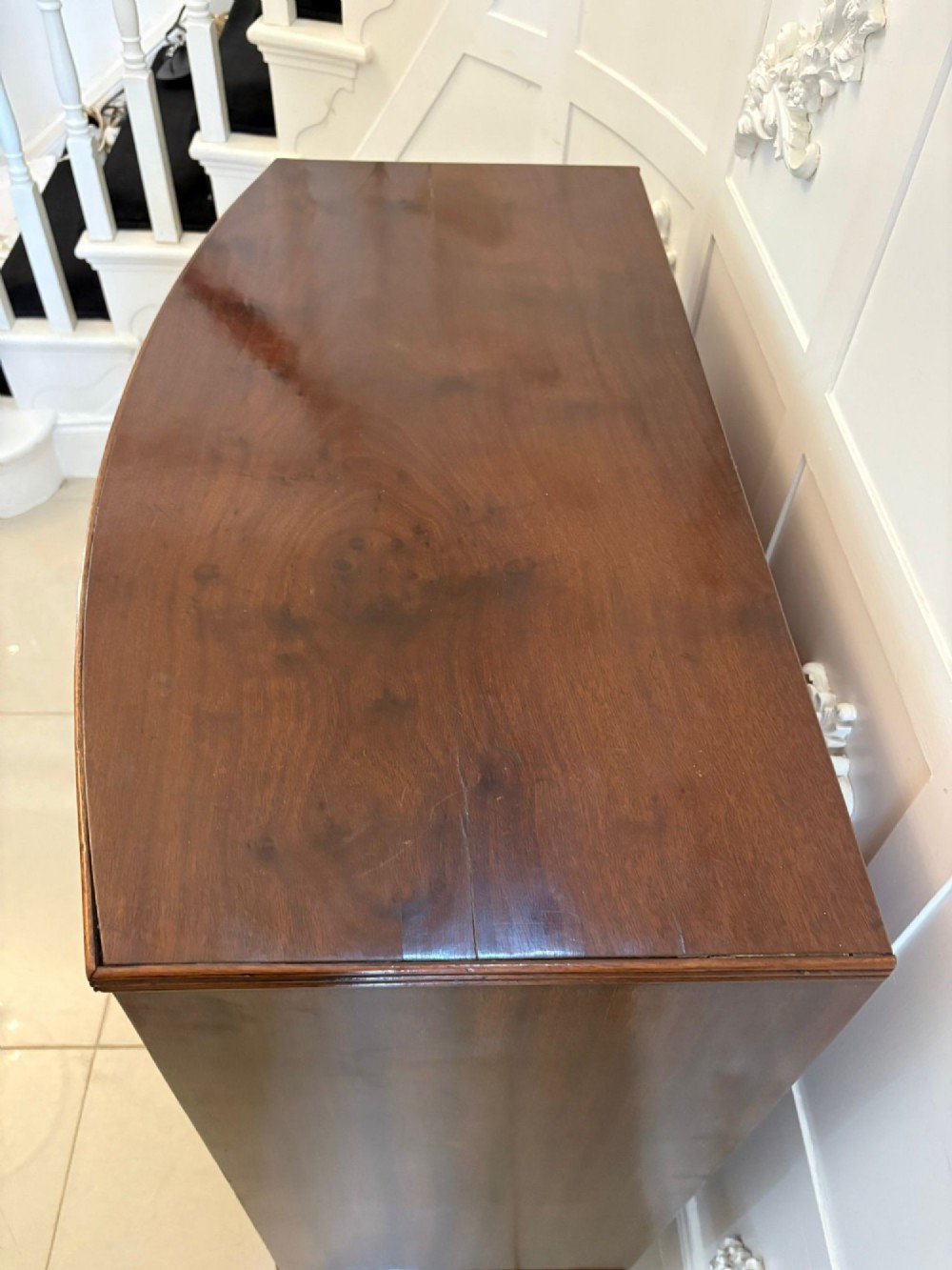 A George III mahogany bowfront chest of drawers featuring two short drawers over three long drawers with oval brass handles and splayed bracket feet. View VIII