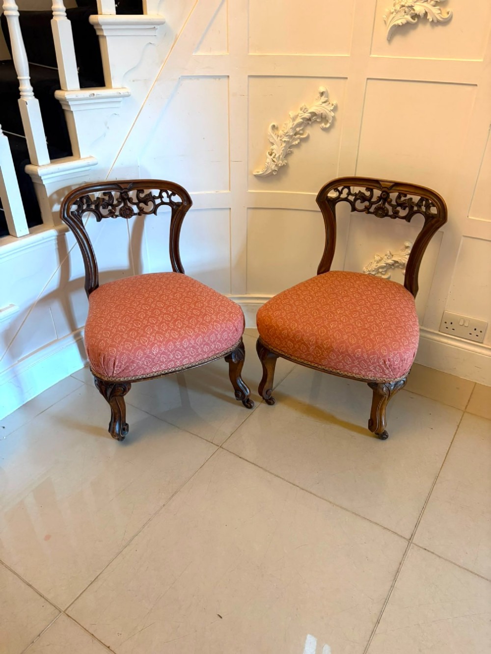 A pair of Victorian carved walnut side chairs with openwork backs and terracotta patterned fabric seats.