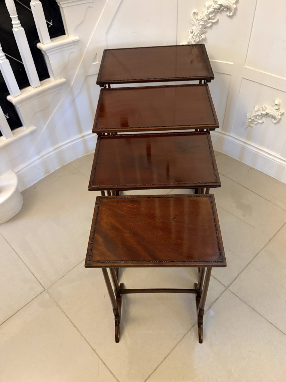 A set of four graduated Edwardian mahogany tables standing stepped outwards to display their inlaid boxwood borders and turned supports.