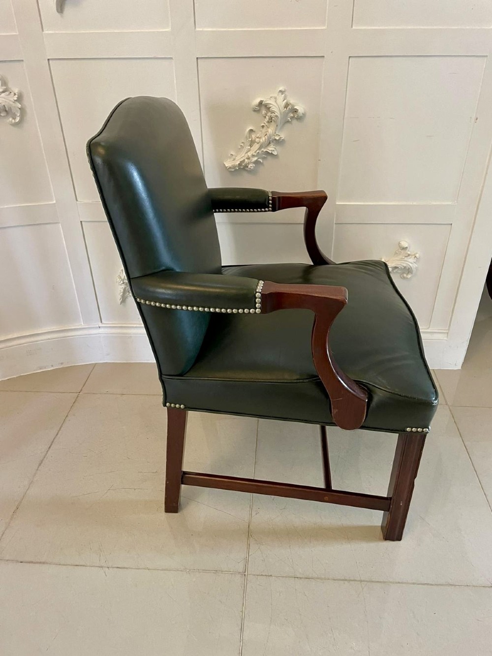 A pair of dark green leather armchairs with polished mahogany frames and brass stud detailing along the upholstery edges. View III