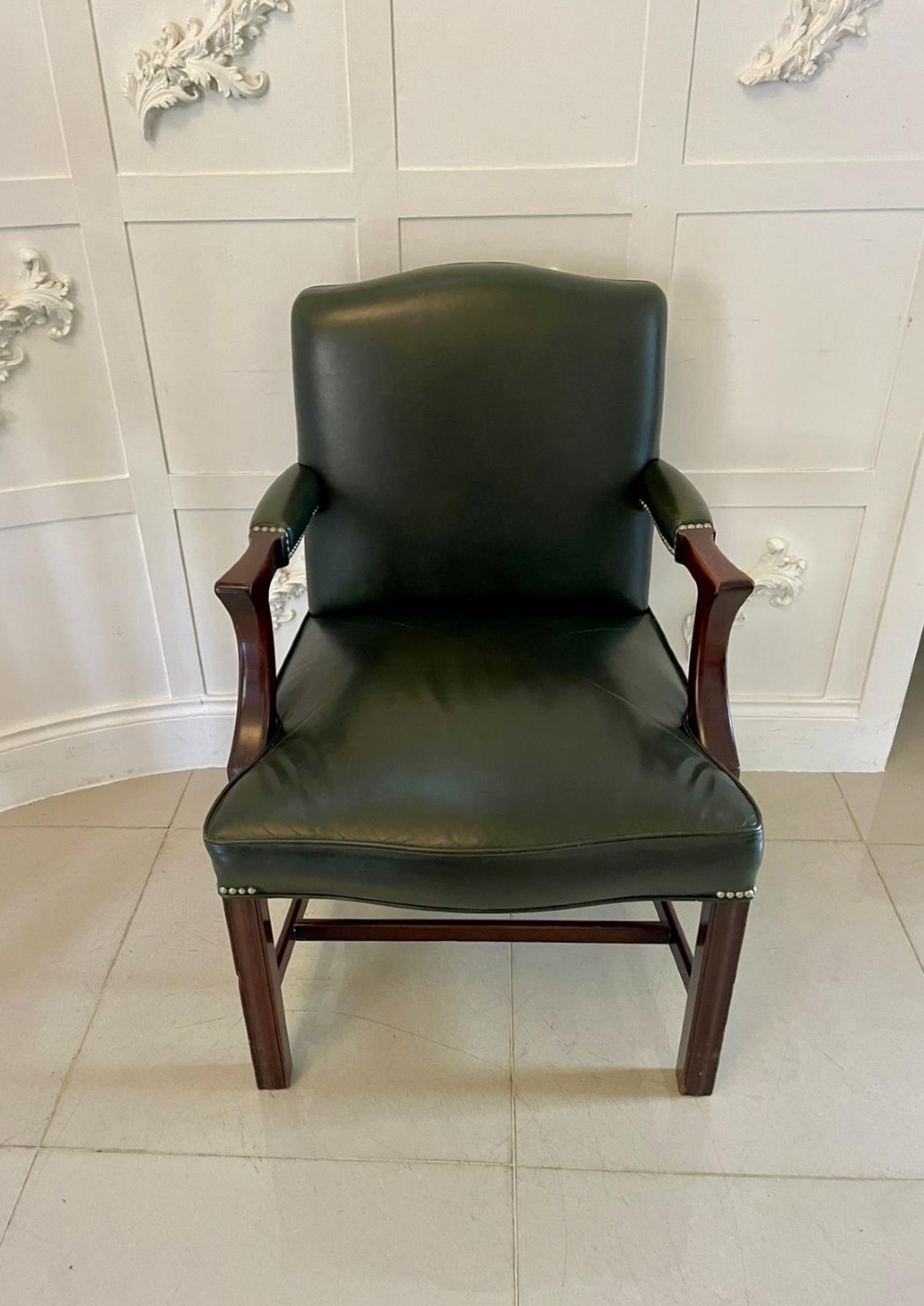 A pair of dark green leather armchairs with polished mahogany frames and brass stud detailing along the upholstery edges. View IV