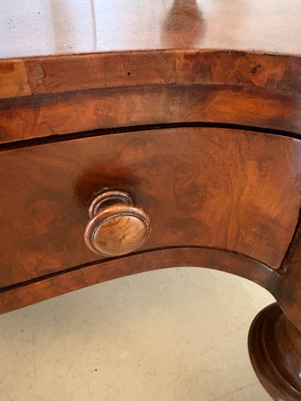 A Victorian burr walnut three-tier serpentine-shaped whatnot featuring turned corner supports, a pierced brass gallery rim, a single bottom drawer, and brass castors. View VIII