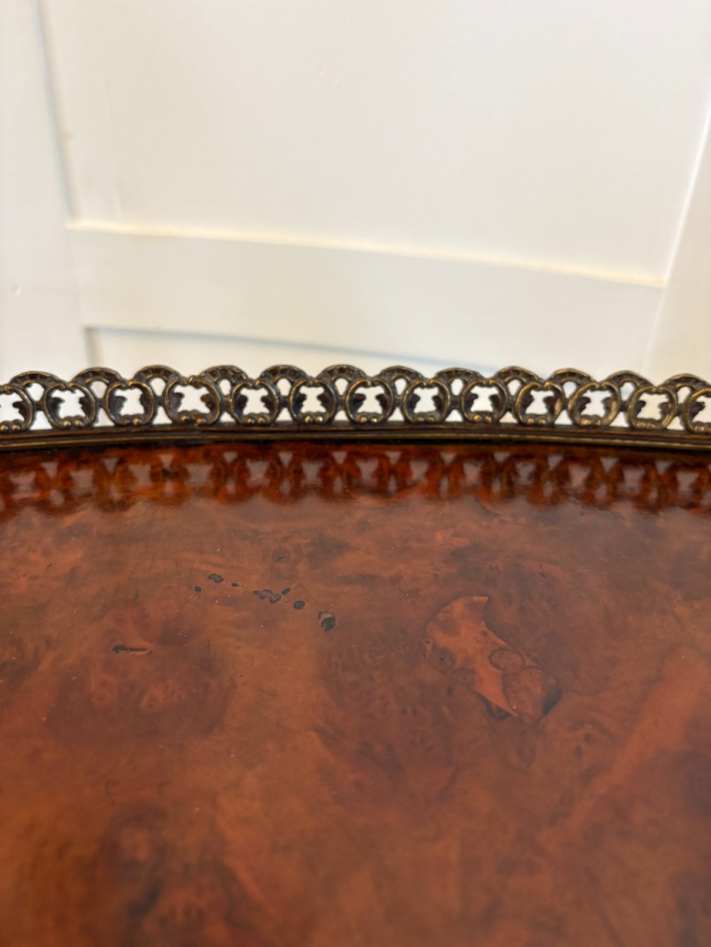 A Victorian burr walnut three-tier serpentine-shaped whatnot featuring turned corner supports, a pierced brass gallery rim, a single bottom drawer, and brass castors. View XI