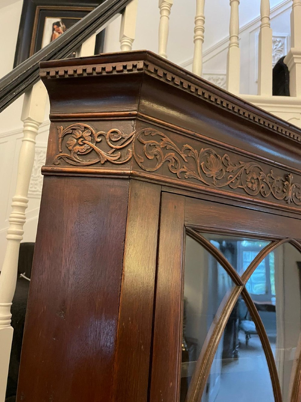 A tall mahogany corner cabinet with two astragal glazed doors featuring curved oval tracery and a carved foliate frieze. View II