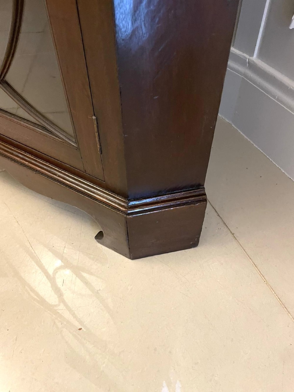 A tall mahogany corner cabinet with two astragal glazed doors featuring curved oval tracery and a carved foliate frieze. View X