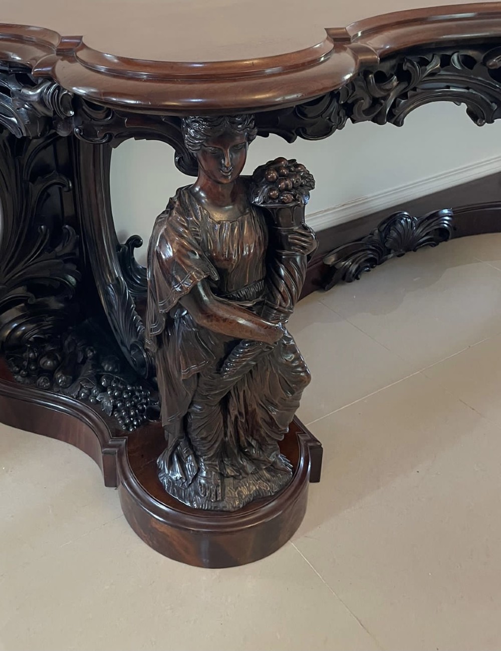 An exceptionally large Victorian dark mahogany console table featuring carved caryatid figures, elaborate scrollwork, a large arched mirror back, and a contoured plinth base. View II