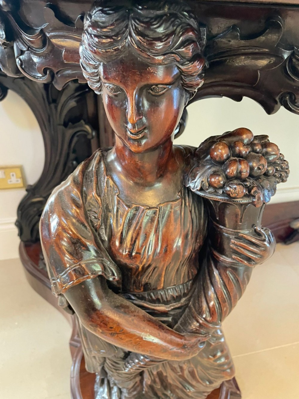 An exceptionally large Victorian dark mahogany console table featuring carved caryatid figures, elaborate scrollwork, a large arched mirror back, and a contoured plinth base. View III