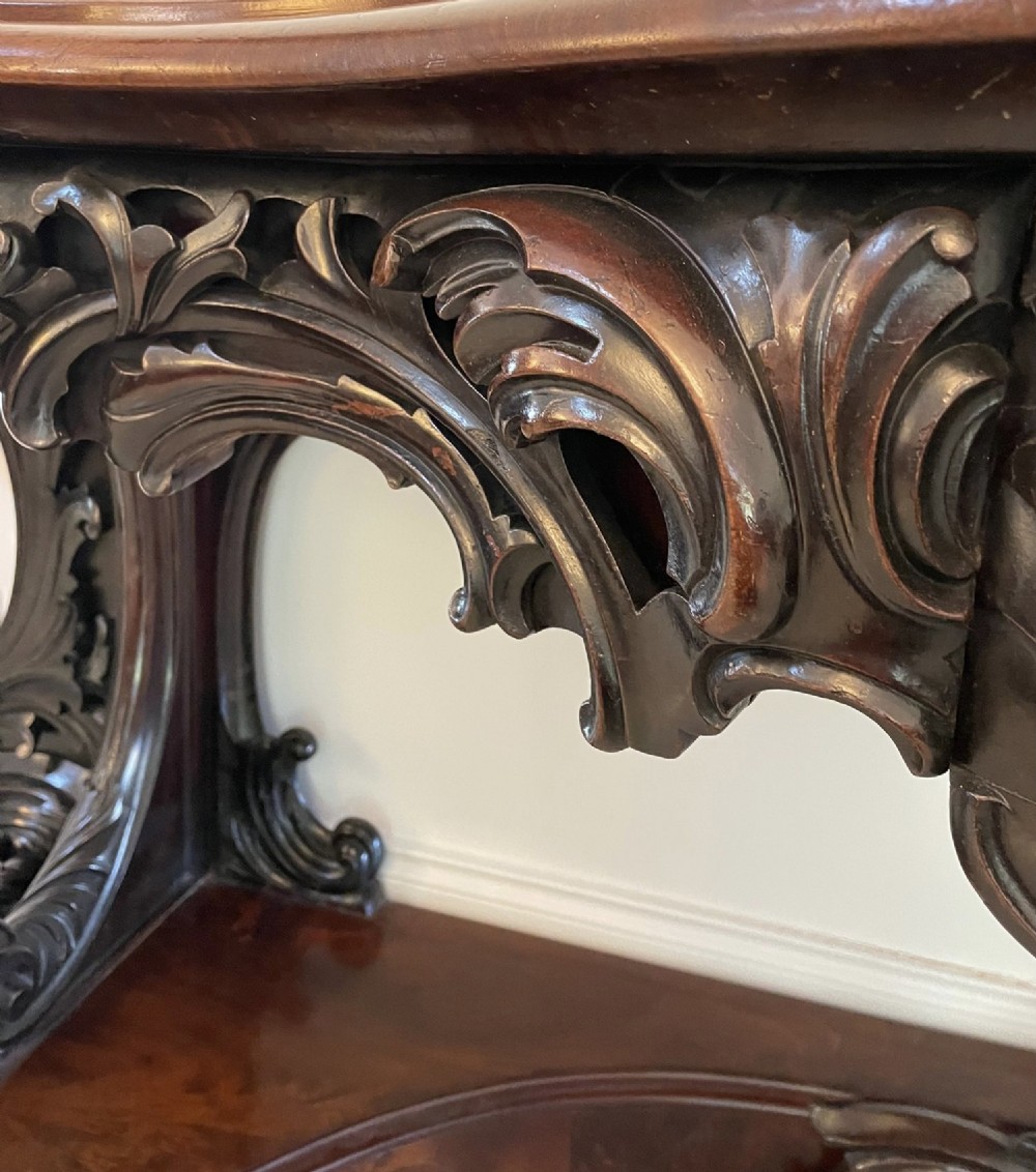 An exceptionally large Victorian dark mahogany console table featuring carved caryatid figures, elaborate scrollwork, a large arched mirror back, and a contoured plinth base. View V