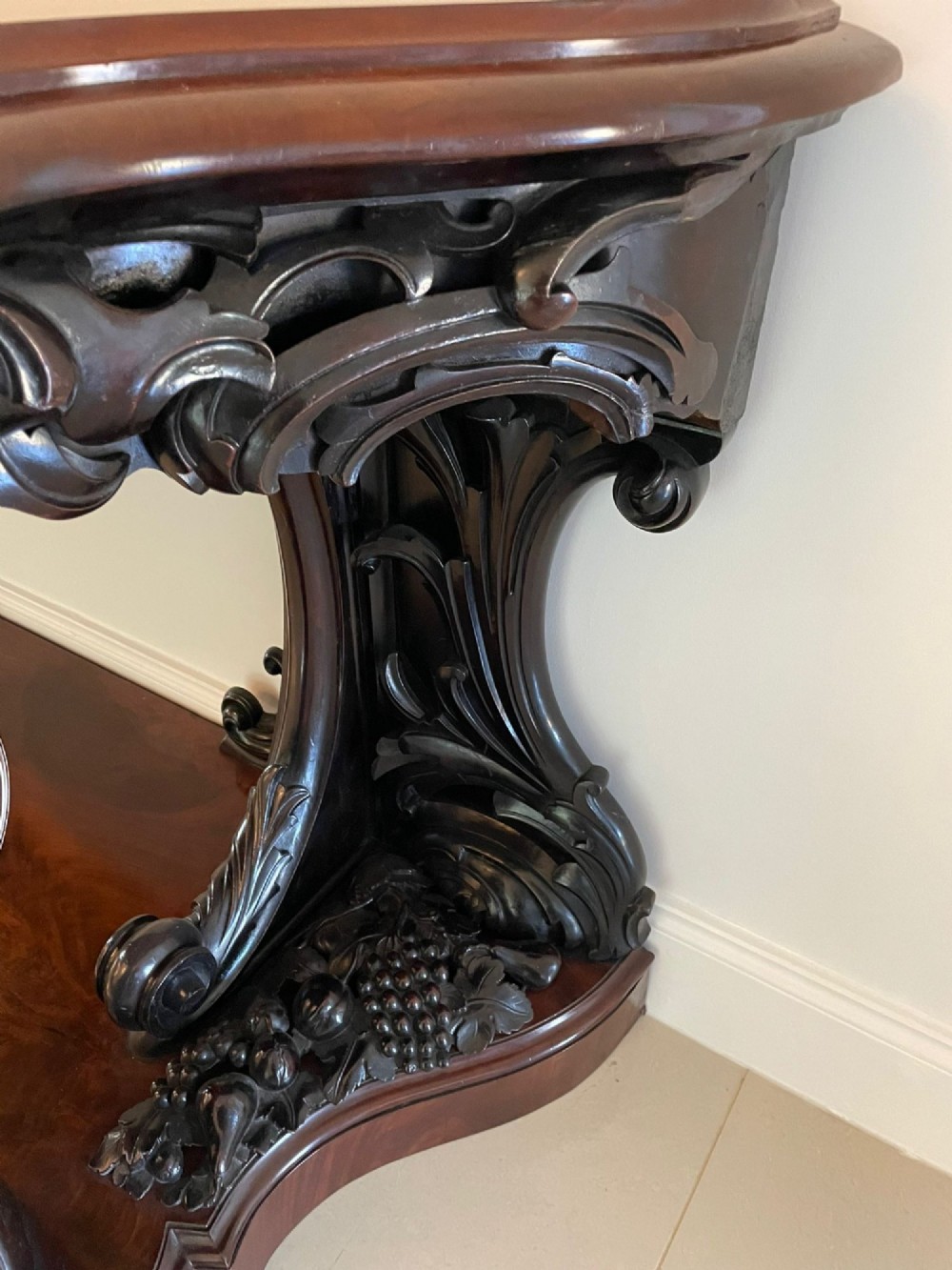 An exceptionally large Victorian dark mahogany console table featuring carved caryatid figures, elaborate scrollwork, a large arched mirror back, and a contoured plinth base. View VII