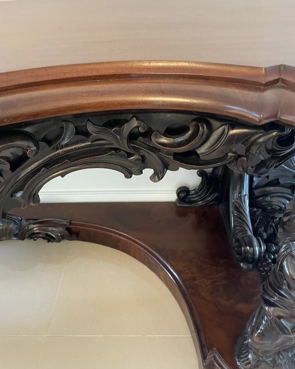 An exceptionally large Victorian dark mahogany console table featuring carved caryatid figures, elaborate scrollwork, a large arched mirror back, and a contoured plinth base. View VIII
