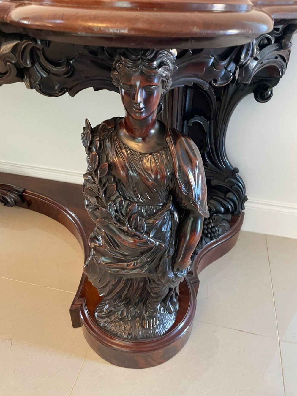 An exceptionally large Victorian dark mahogany console table featuring carved caryatid figures, elaborate scrollwork, a large arched mirror back, and a contoured plinth base. View IX