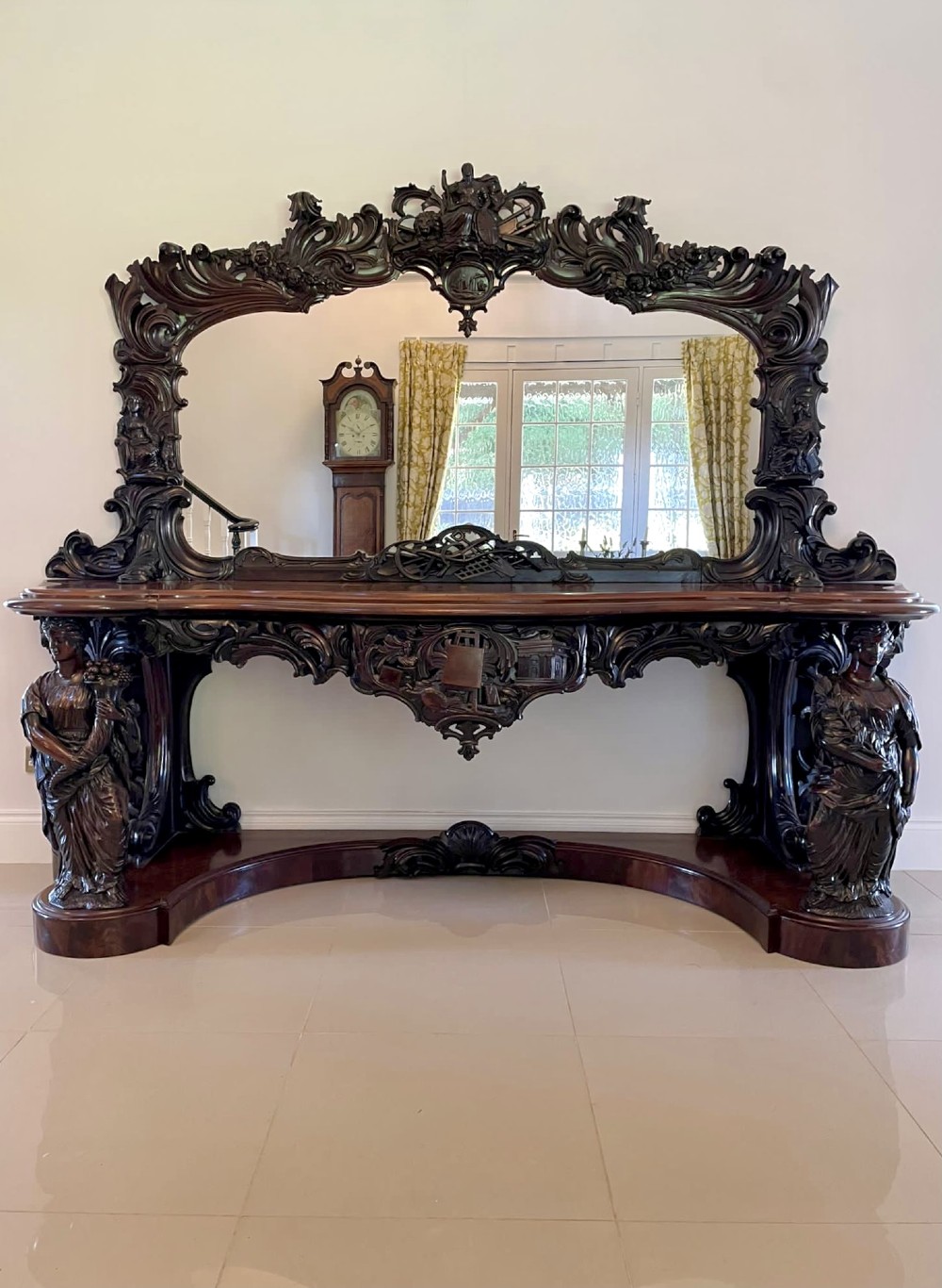 An exceptionally large Victorian dark mahogany console table featuring carved caryatid figures, elaborate scrollwork, a large arched mirror back, and a contoured plinth base.
