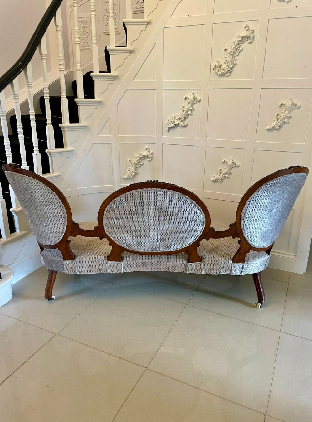 A Victorian carved walnut cameo back sofa featuring three oval upholstered panels, floral crestings, and cabriole legs on castors. View II
