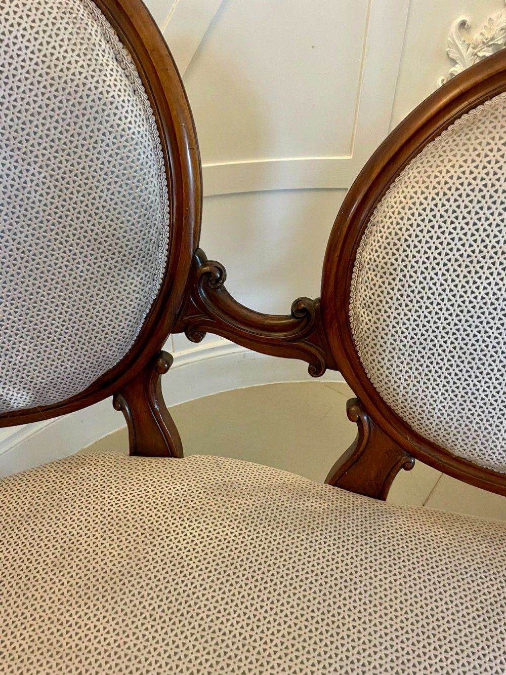 A Victorian carved walnut cameo back sofa featuring three oval upholstered panels, floral crestings, and cabriole legs on castors. View V