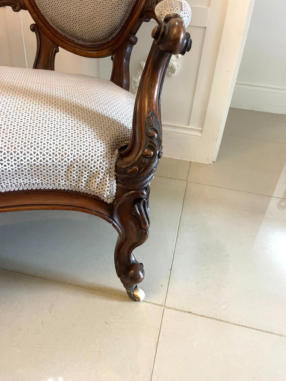 A Victorian carved walnut cameo back sofa featuring three oval upholstered panels, floral crestings, and cabriole legs on castors. View VI