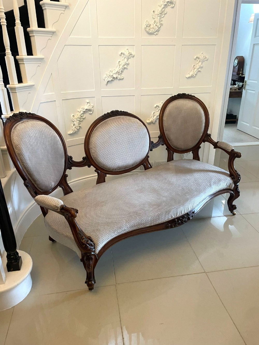 A Victorian carved walnut cameo back sofa featuring three oval upholstered panels, floral crestings, and cabriole legs on castors. View X