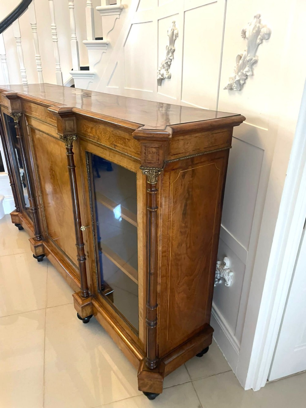 A Victorian burr walnut credenza featuring a central marquetry inlaid timber door flanked by two glazed side cabinets and turned column supports. View XII