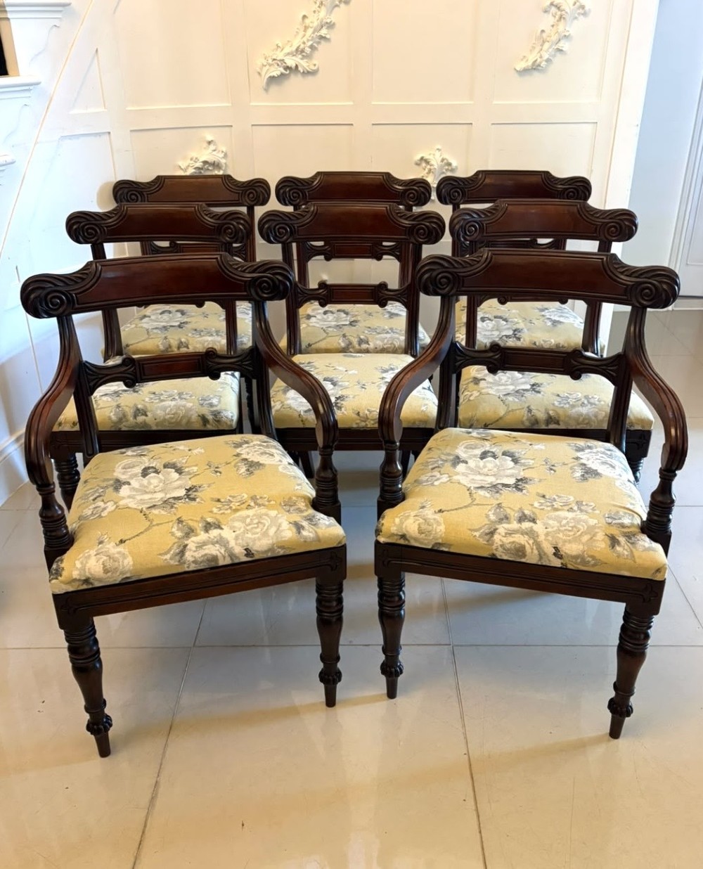 A set of eight Regency mahogany dining chairs comprising six side chairs and two carver armchairs with scroll-carved top rails and turned front legs. View II