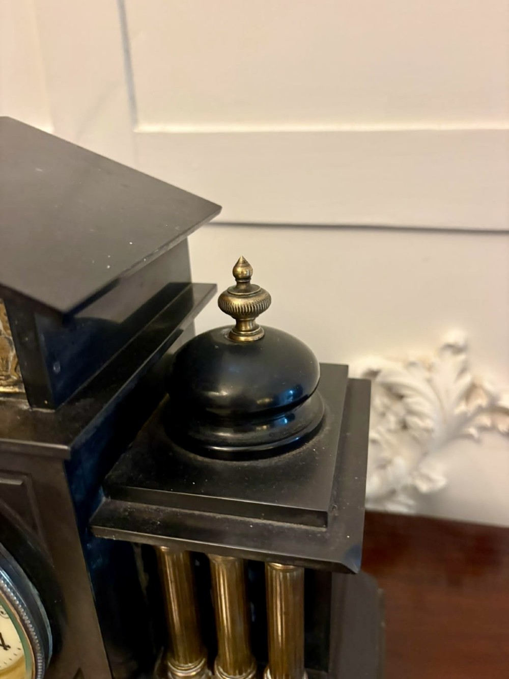 An architectural black marble mantel clock featuring gilt brass columns, a relief frieze panel depicting classical figures, and a round dial with Arabic numerals. View VIII