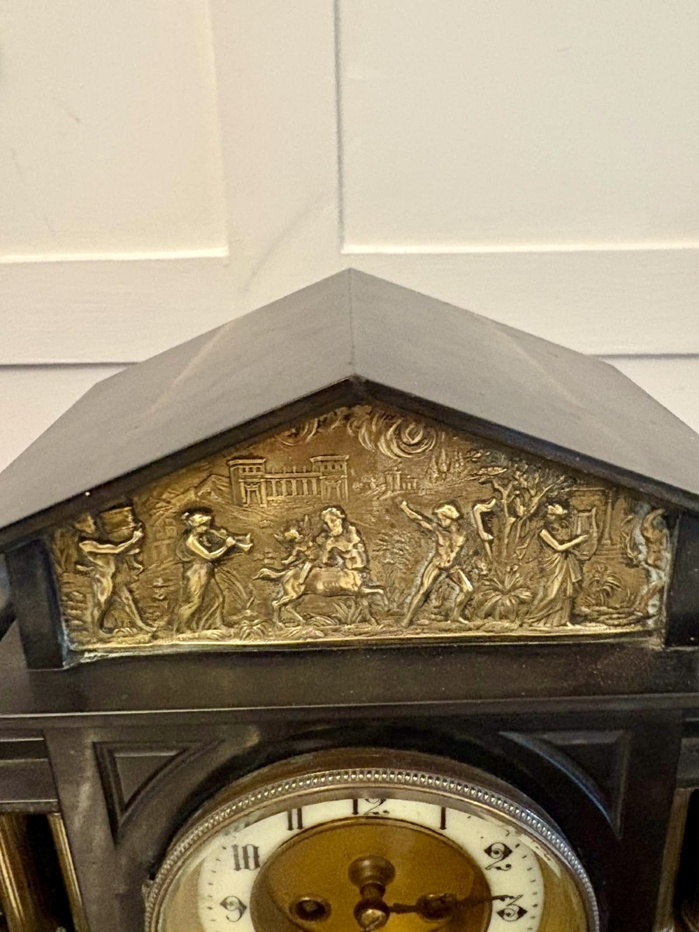 An architectural black marble mantel clock featuring gilt brass columns, a relief frieze panel depicting classical figures, and a round dial with Arabic numerals. View IX