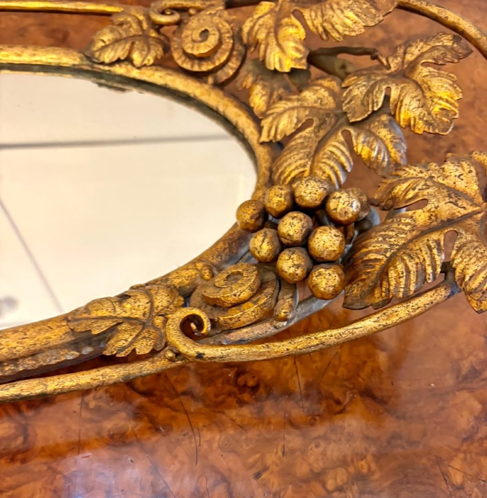 An oval gilt metal tray featuring a central mirror panel surrounded by an ornate border of sculpted grapevines, leaves, and grape clusters. View III