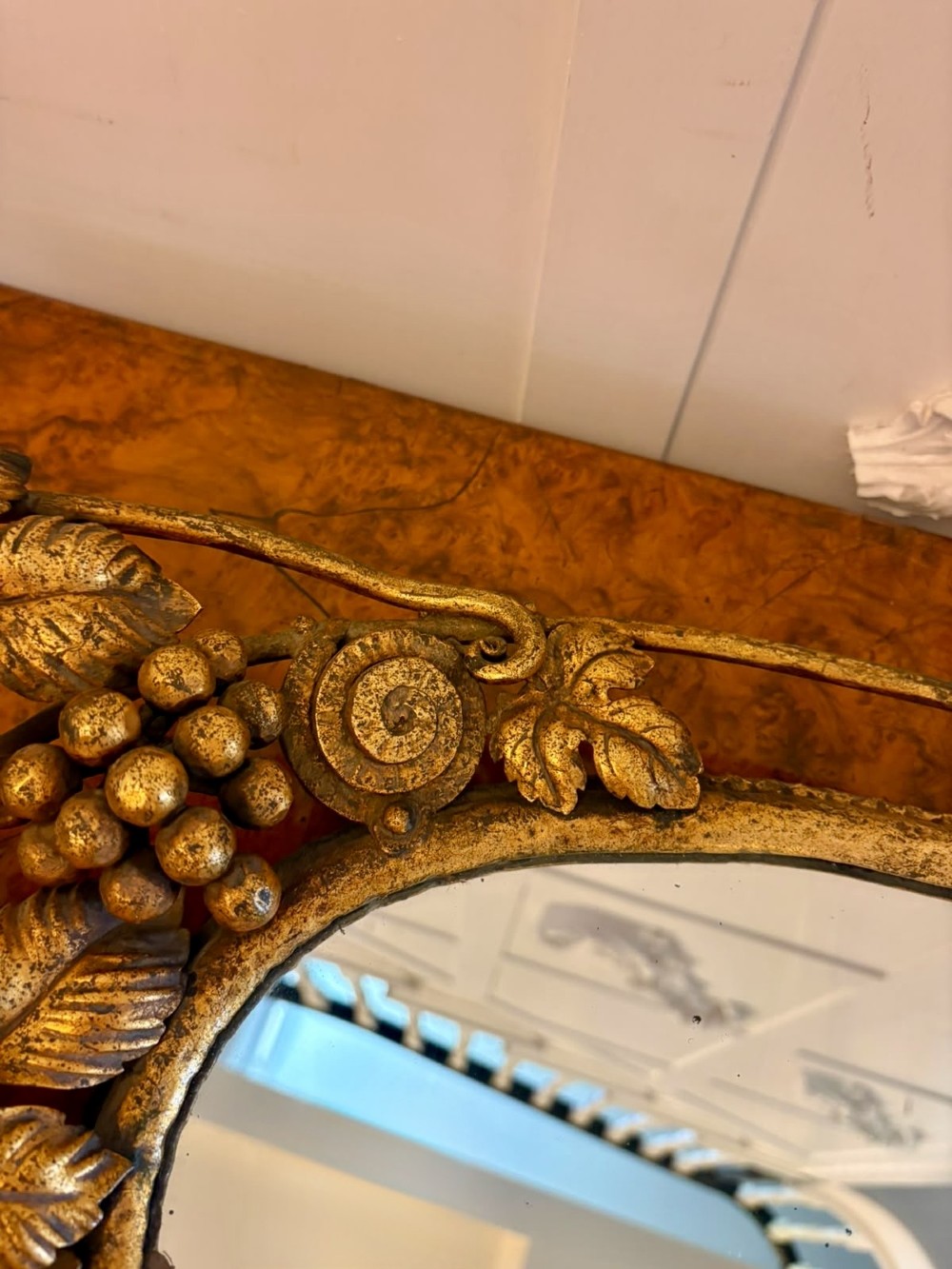An oval gilt metal tray featuring a central mirror panel surrounded by an ornate border of sculpted grapevines, leaves, and grape clusters. View V