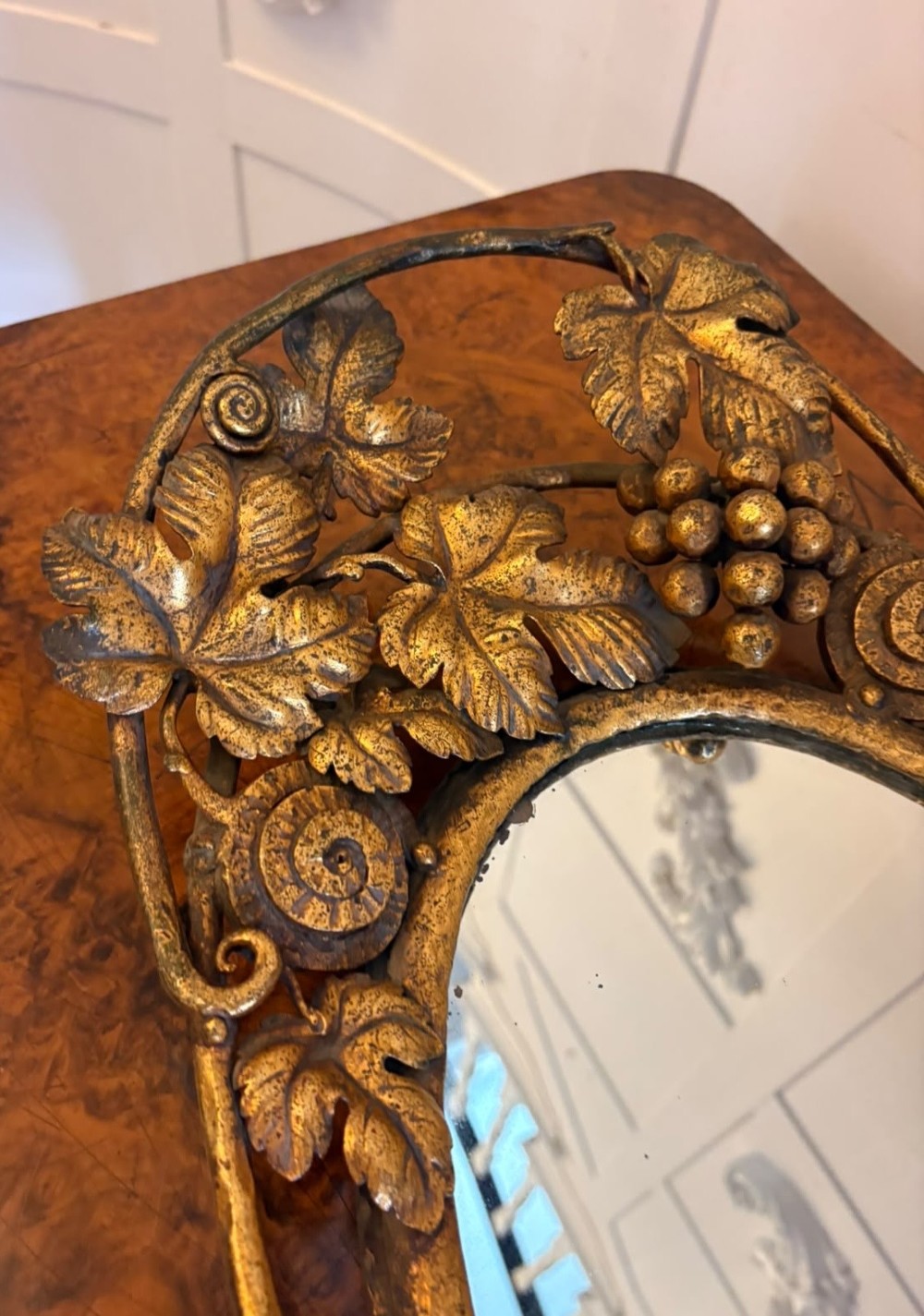 An oval gilt metal tray featuring a central mirror panel surrounded by an ornate border of sculpted grapevines, leaves, and grape clusters. View VII