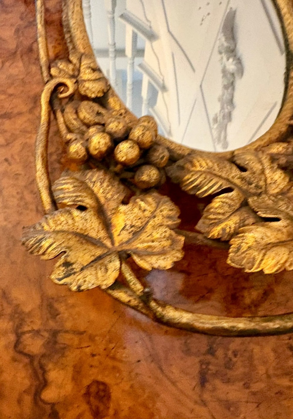 An oval gilt metal tray featuring a central mirror panel surrounded by an ornate border of sculpted grapevines, leaves, and grape clusters. View IX