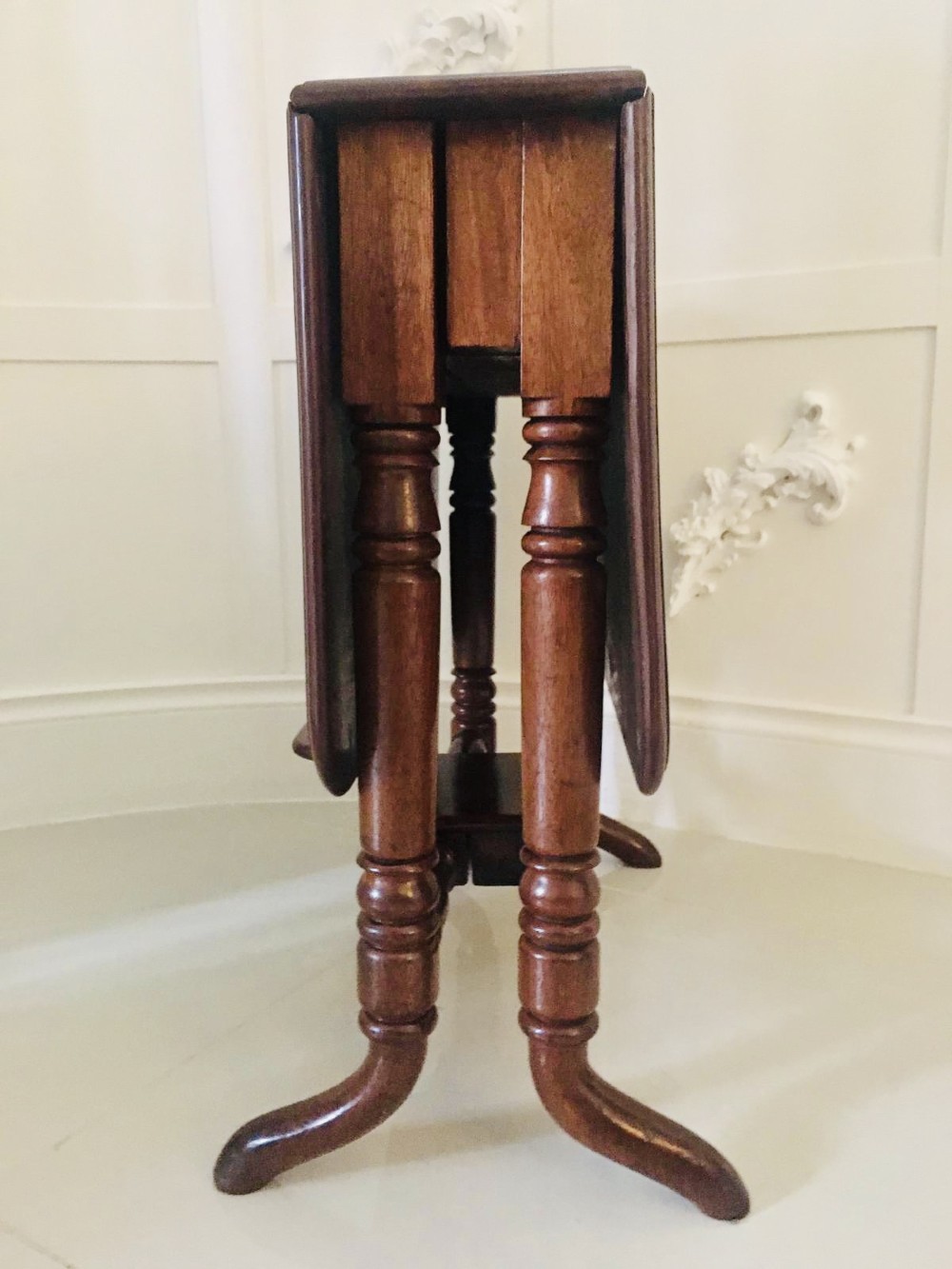 An antique mahogany Sutherland table featuring hinged drop leaves, turned legs with horizontal stretchers, and a central wooden base block. View III