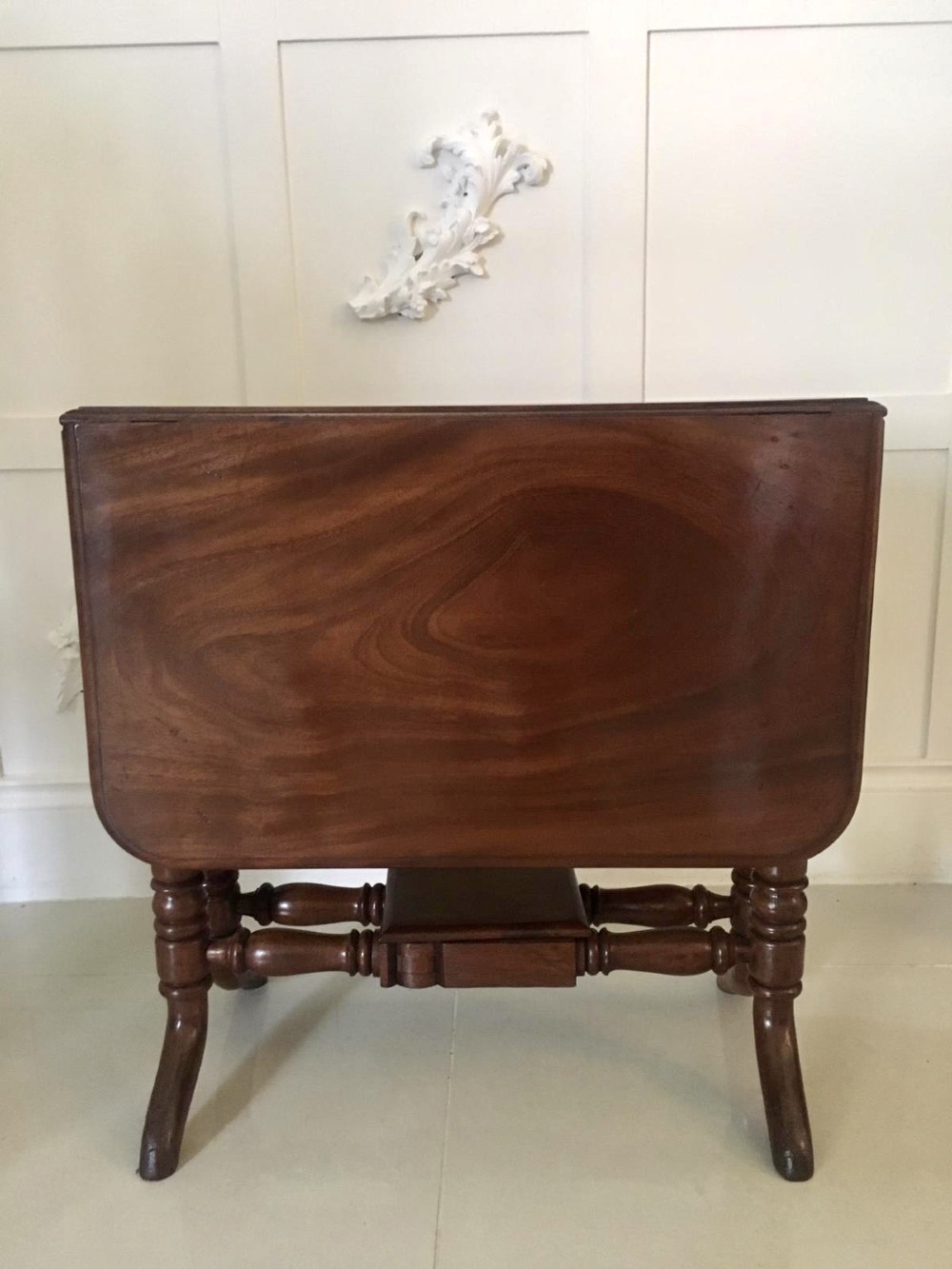 An antique mahogany Sutherland table featuring hinged drop leaves, turned legs with horizontal stretchers, and a central wooden base block. View V