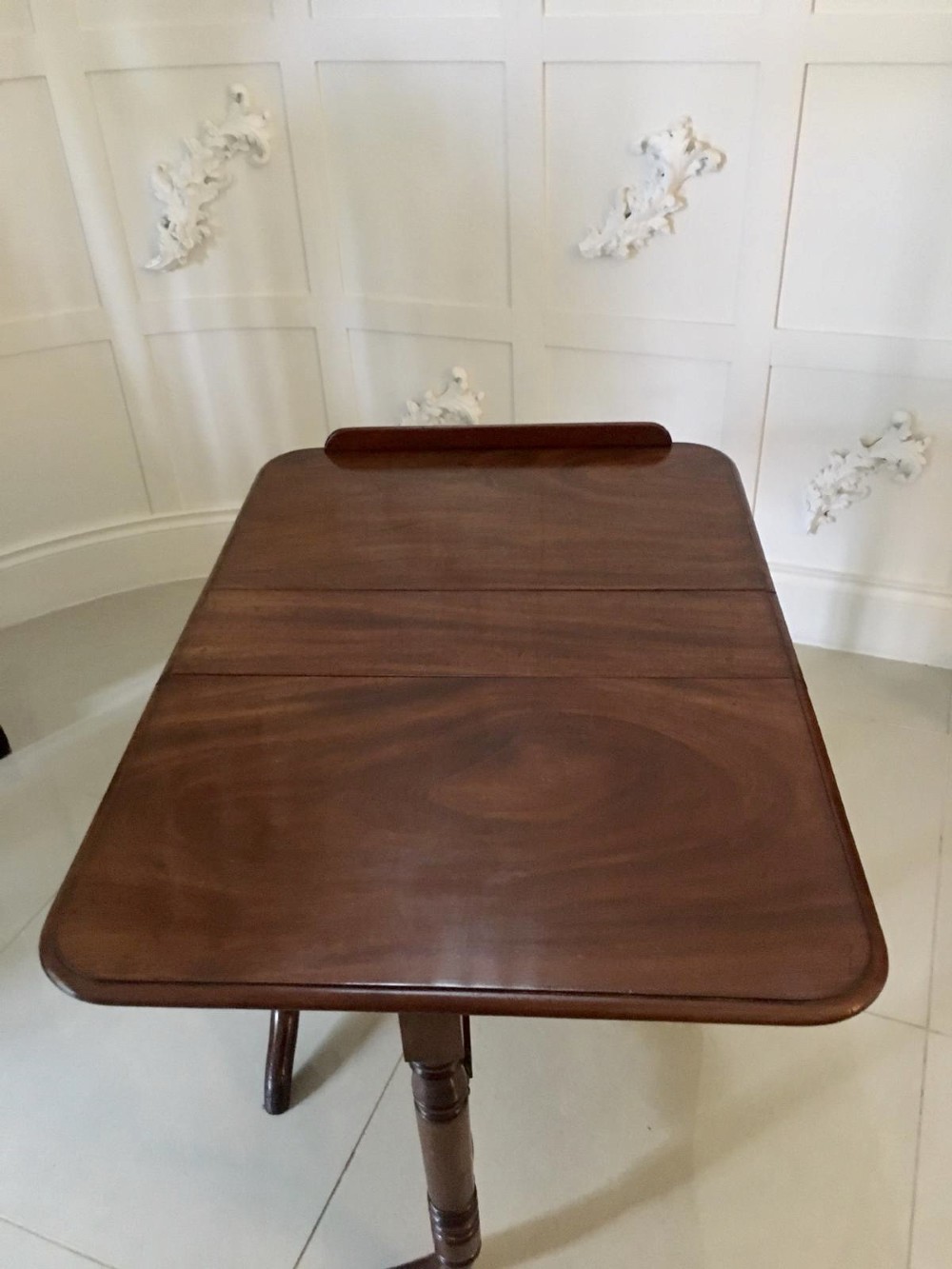 An antique mahogany Sutherland table featuring hinged drop leaves, turned legs with horizontal stretchers, and a central wooden base block. View VI
