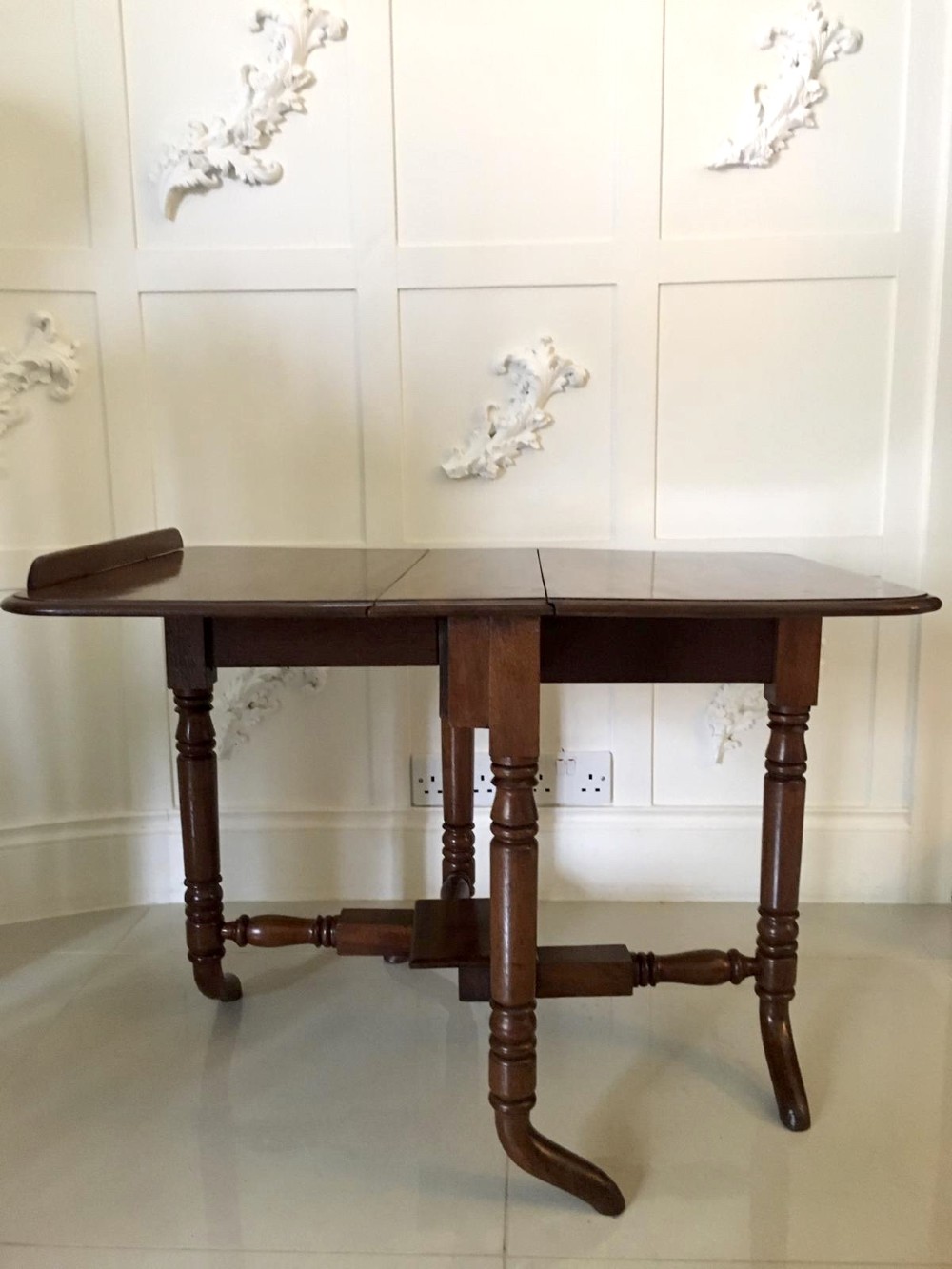 An antique mahogany Sutherland table featuring hinged drop leaves, turned legs with horizontal stretchers, and a central wooden base block. View VII