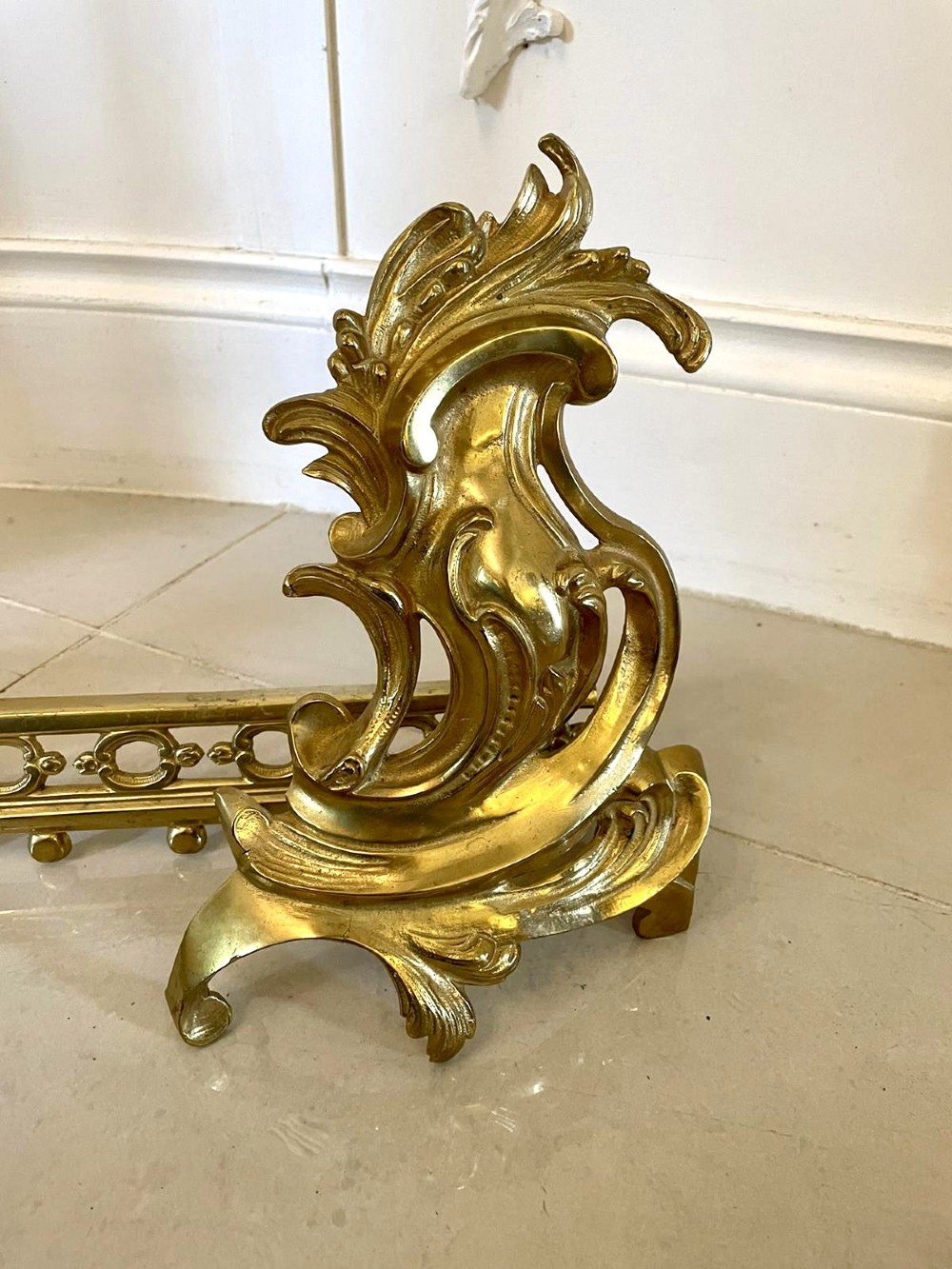 An ornate French Rococo style gilded brass extending fireplace fender with intricate scroll ends and an adjustable central bar. View II