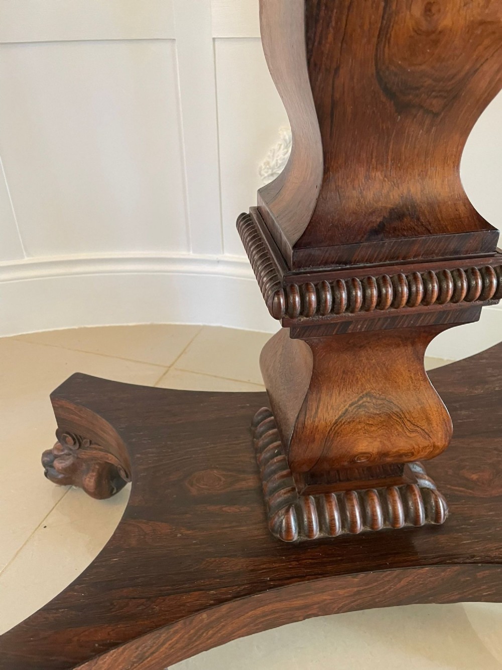 A William IV dark rosewood fold-over card table featuring a gadrooned top edge, scroll carvings, a central pedestal column, and a plinth base on carved claw feet. View V