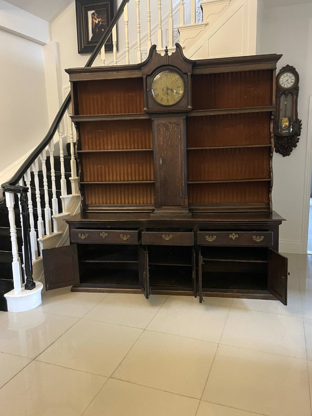 An eighteenth-century dark oak George III dresser featuring an upper shelf rack with an integrated central longcase clock over a base with three drawers and six arched panel cupboard doors. View V