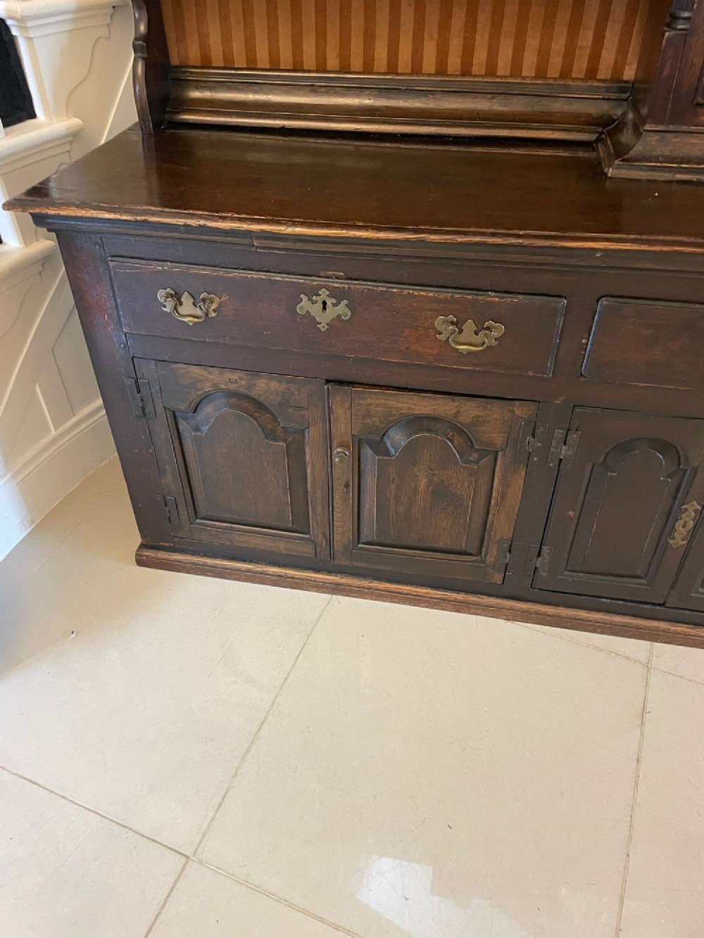 An eighteenth-century dark oak George III dresser featuring an upper shelf rack with an integrated central longcase clock over a base with three drawers and six arched panel cupboard doors. View IX