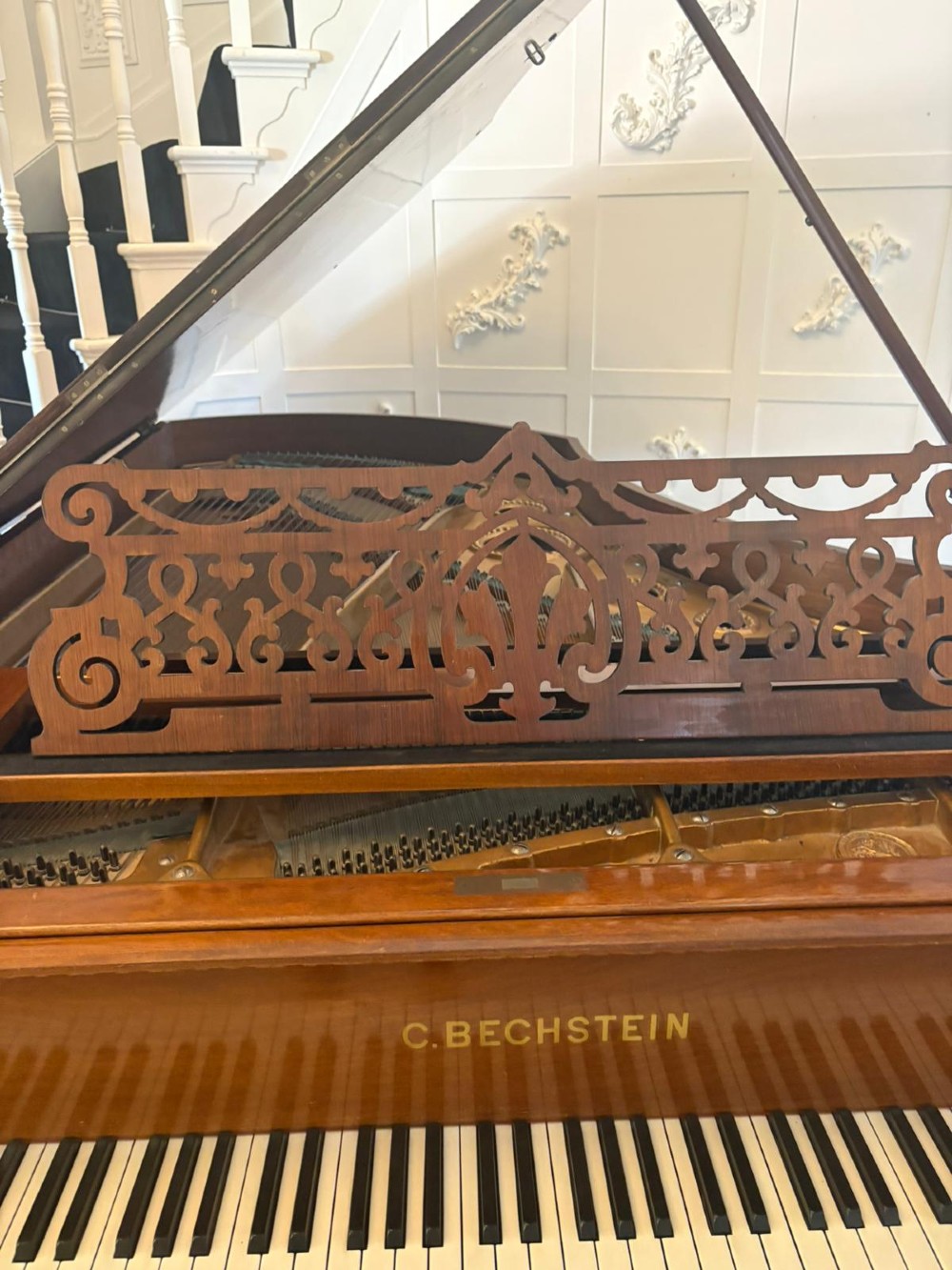 A late Victorian C. Bechstein Model V boudoir grand piano in rosewood, featuring a open top lid, carved fretwork music desk, turned legs, and brass castors. View XV