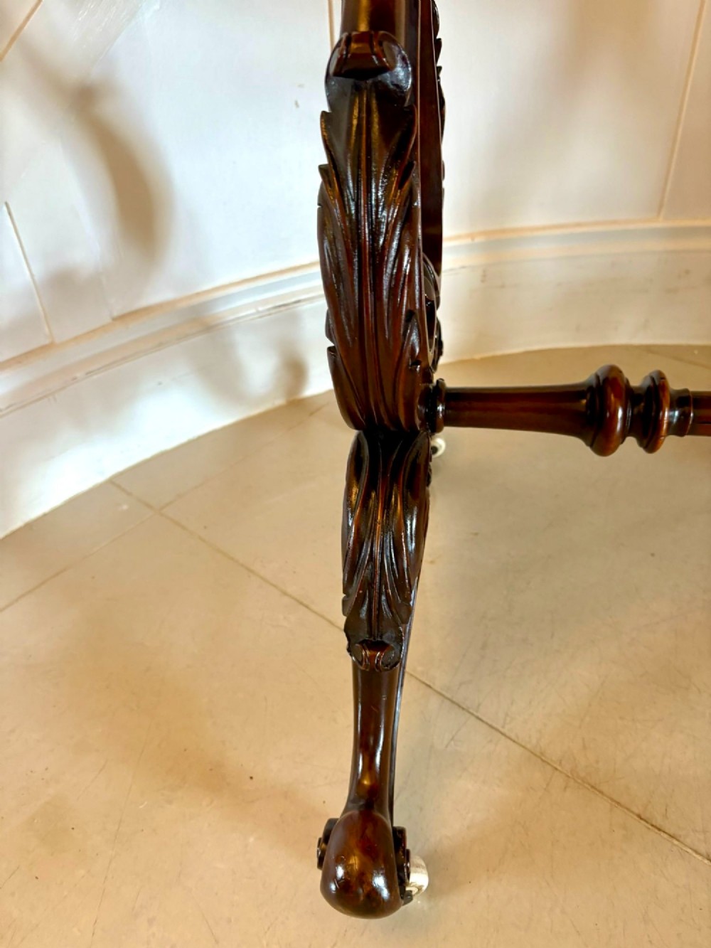 A Victorian burr walnut centre table with a serpentine shaped top, figured wood grain, detailed carved end supports, and a turned stretcher on small castors. View III