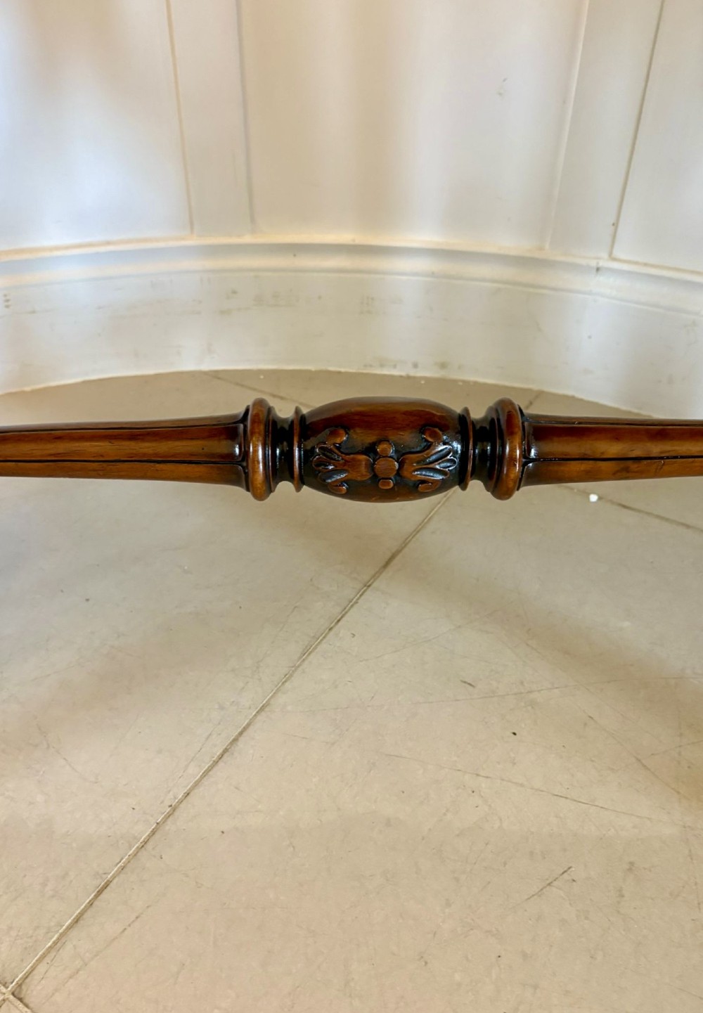 A Victorian burr walnut centre table with a serpentine shaped top, figured wood grain, detailed carved end supports, and a turned stretcher on small castors. View VI