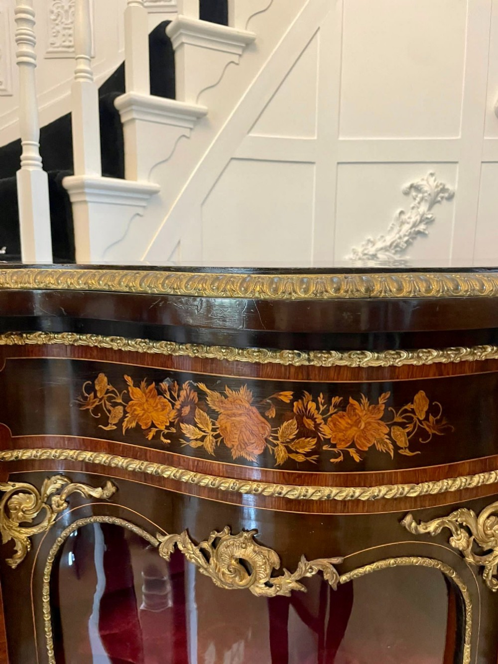 A dark wood Victorian serpentine credenza with floral marquetry inlay, gilt ormolu mounts, and two curved glass display doors. View VIII