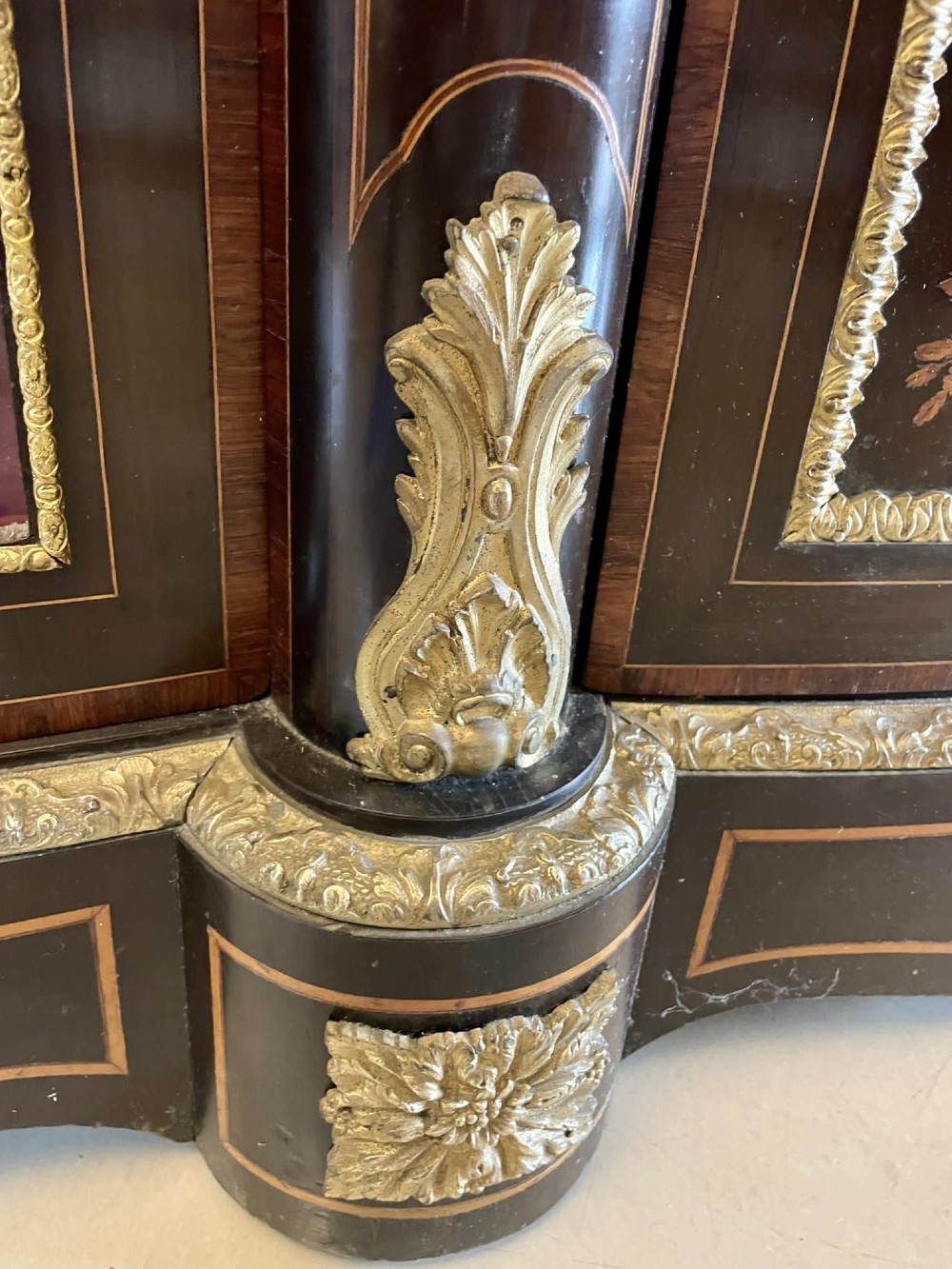 A dark wood Victorian serpentine credenza with floral marquetry inlay, gilt ormolu mounts, and two curved glass display doors. View IX