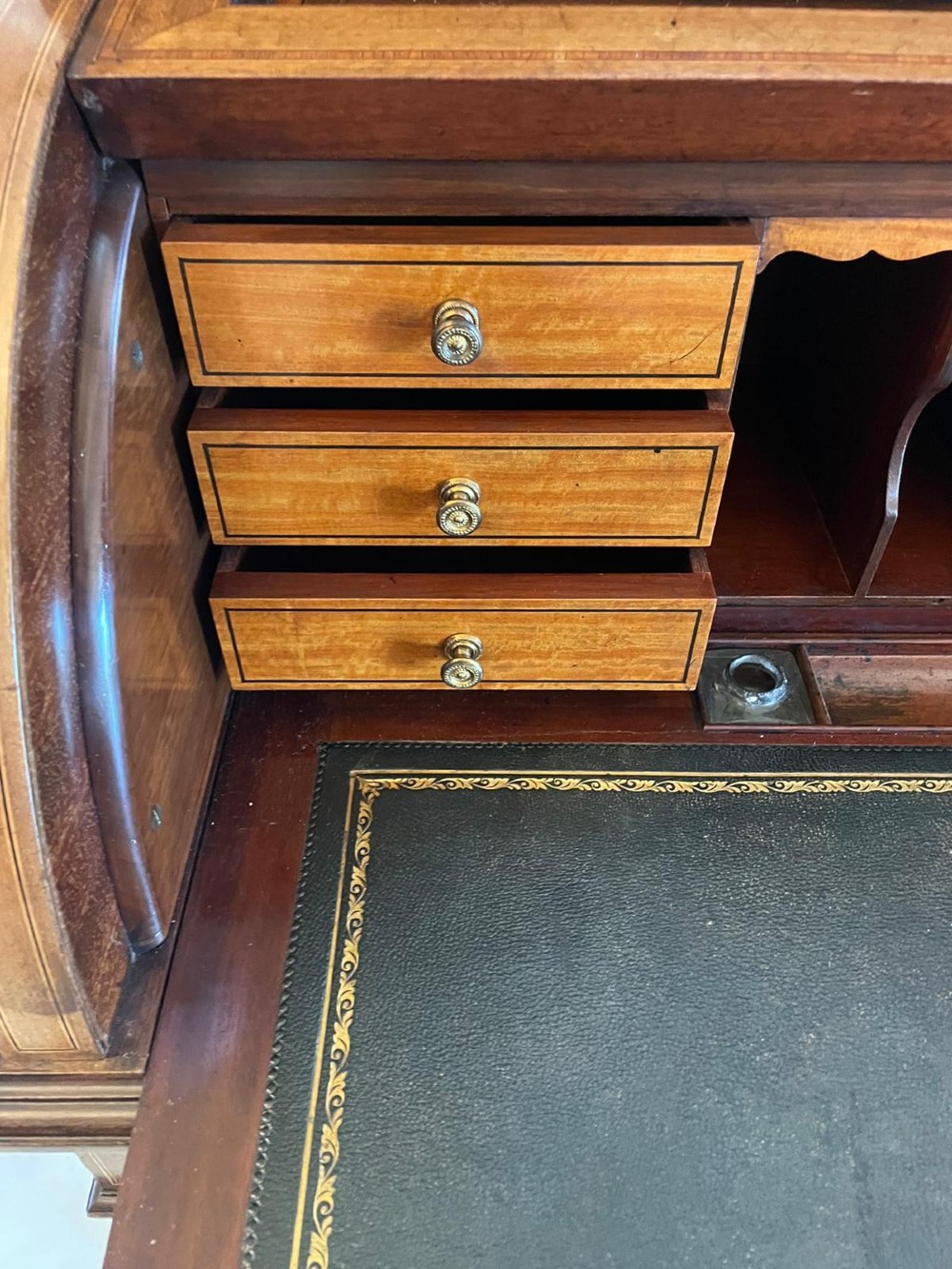 An Edwardian mahogany cylinder writing desk featuring satinwood inlay, brass gallery top rail, and tapered square legs. View VI
