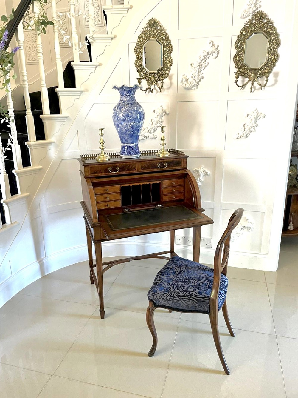 An Edwardian mahogany cylinder writing desk featuring satinwood inlay, brass gallery top rail, and tapered square legs. View X