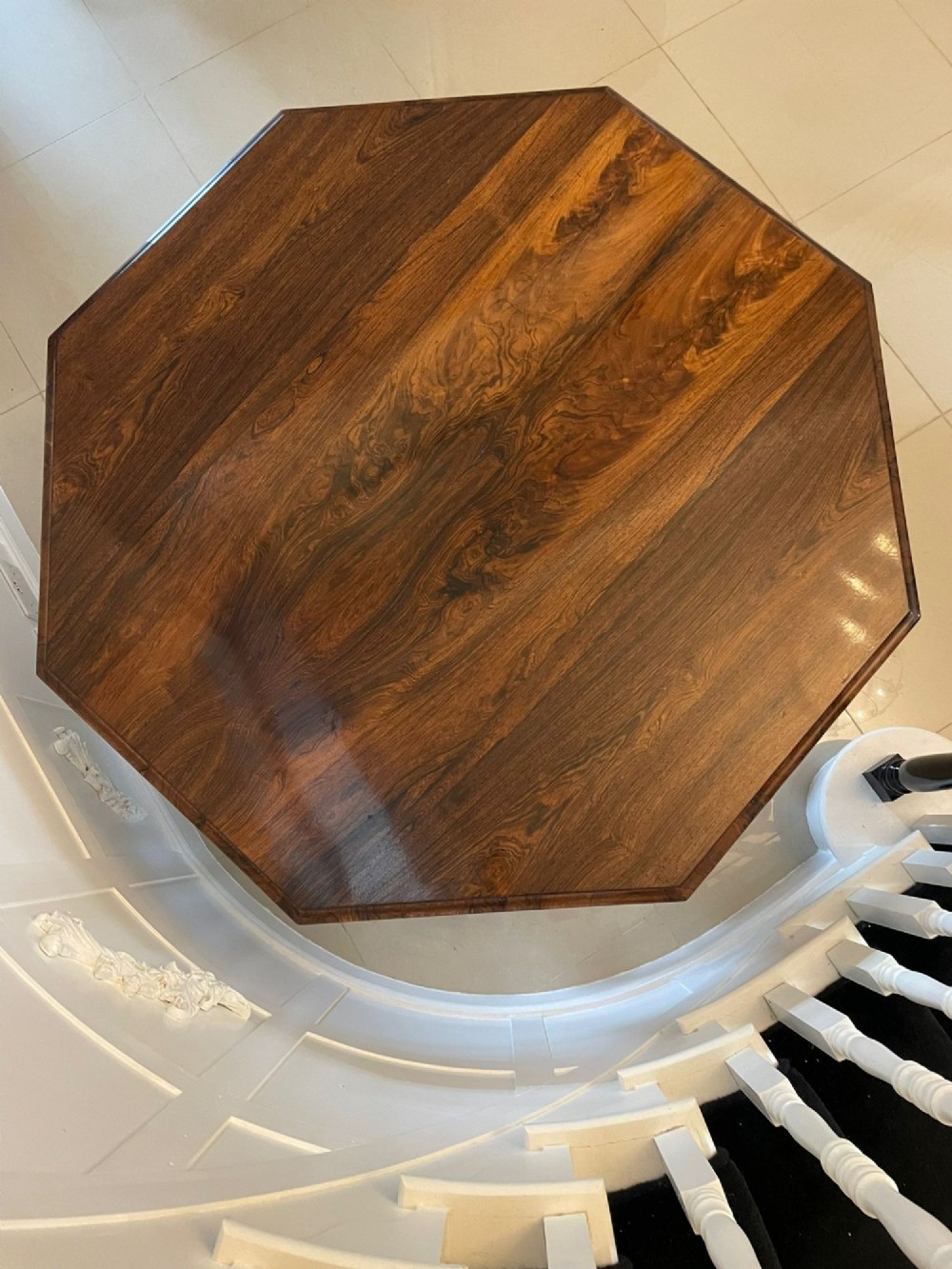 An Early Victorian octagonal rosewood tilt-top centre table with a highly figured grain surface resting on a carved pedestal base with scroll feet. View IV