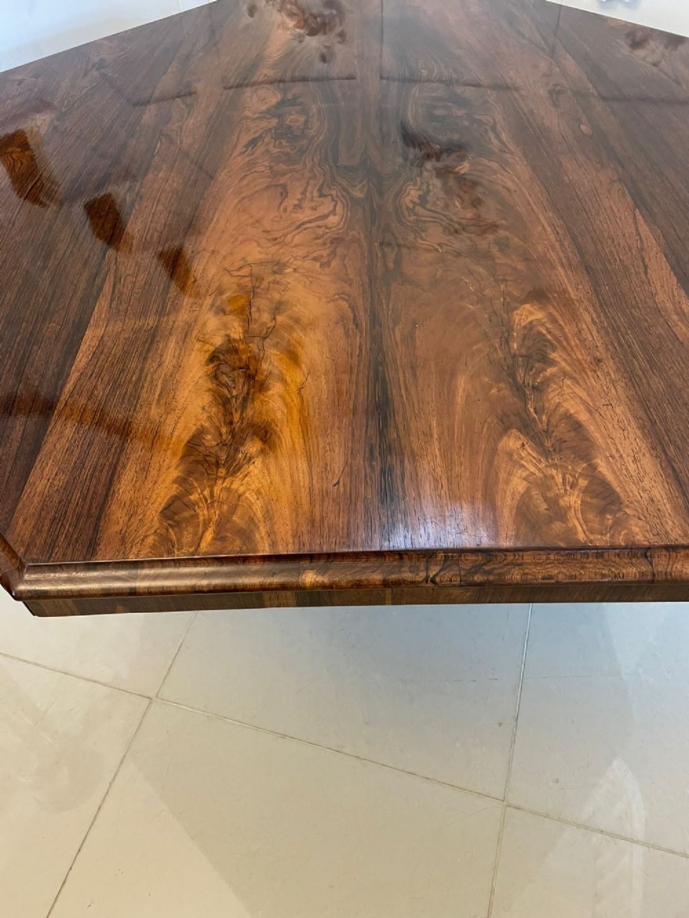 An Early Victorian octagonal rosewood tilt-top centre table with a highly figured grain surface resting on a carved pedestal base with scroll feet. View VI